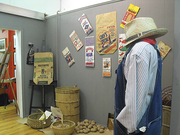 The Blue Moon Gallery recently opened its newest its newest exhibition, "Art of the Harvest," to rekindle memories of a time when everyone picked potatoes by hand during the harvest and machinery was a luxury rather than the norm. Here, potato bags cover the walls and a mannequin is dressed in a customary picker's outfit, complete with overalls, hat and durable gloves. (BANGOR DAILY NEWS PHOTO BY JEN LYNDS) The Blue Moon Gallery recently opened its newest its newest exhibition, "Art of the Harvest," to rekindle memories of a time when everyone picked potatoes by hand during the harvest and machinery was a luxury rather than the norm. Here, potato bags cover the walls and a mannequin is dressed in a customary picker's outfit, complete with overalls, hat and durable gloves. (BANGOR DAILY NEWS PHOTO BY JEN LYNDS)