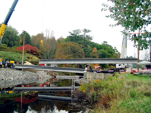 Two large cranes hoist an 88-foot, 80,000-pound precast concrete beam into place over the Orland River on Friday. The beams will form the base for the concrete deck of the new bridge being constructed by crews from Lane Construction. BANGOR DAILY NEWS PHOTO BY RICH HEWITT Two large cranes hoist an 88-foot, 80,000-pound precast concrete beam into place over the Orland River on Friday. The beams will form the base for the concrete deck of the new bridge being constructed by crews from Lane Construction. BANGOR DAILY NEWS PHOTO BY RICH HEWITT