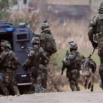 Members of the Maine State Police tactical team gear up at a staging area on Smith Road in Corinna as they respond to another possible siting of suspect Perley Goodrich Jr. late Wednesday afternoon. A man was seen along a road in the vicinity of the Pratt and Smith Roads around 3 p.m. Wednesday. (Bangor Daily News/John Clarke Russ)