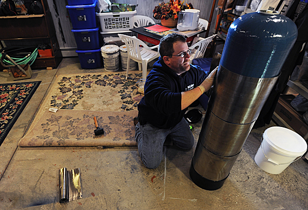 Nathan Chaffee, an employee of Norlen's Water Treatment, wraps a carbon water tank in lead at the home of Ed and Mary Clift in Ellsworth on Wednesday, JAn. 13, 2010. The Clift's home tested high for radon in the water and air. The lead around the tank prevents the filtered radon from leaking radioactive rays. (Bangor Daily News/Kevin Bennett) Nathan Chaffee, an employee of Norlen's Water Treatment, wraps a carbon water tank in lead at the home of Ed and Mary Clift in Ellsworth on Wednesday, JAn. 13, 2010. The Clift's home tested high for radon in the water and air. The lead around the tank prevents the filtered radon from leaking radioactive rays. (Bangor Daily News/Kevin Bennett)