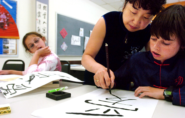 Jing Zhang (center), president of the Bangor Chinese School, helps Tommy McCarthy draw the Chinese character for love as his sister Abby looks on. BANGOR DAILY NEWS PHOTO BY GABOR DEGRE Jing Zhang (center), president of the Bangor Chinese School, helps Tommy McCarthy draw the Chinese character for love as his sister Abby looks on. BANGOR DAILY NEWS PHOTO BY GABOR DEGRE