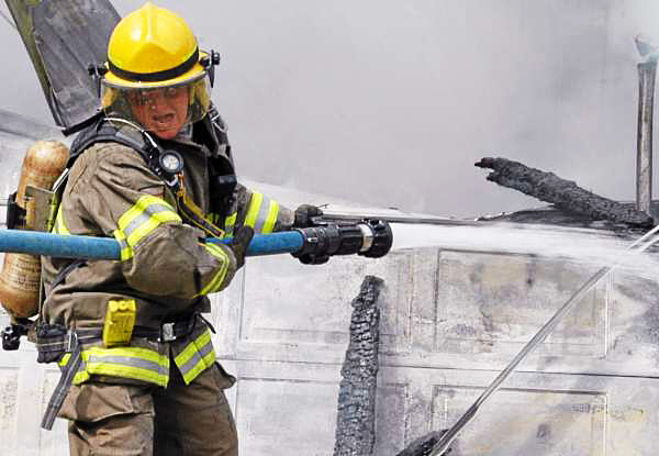 Lincoln Firefighter Donald Olsen shouts to make himself heard over sirens and water as he douses hot spots in a collapsed garage on Lee Road in Lincoln on Saturday. (Bangor Daily News/Nick Sambides Jr.) Lincoln Firefighter Donald Olsen shouts to make himself heard over sirens and water as he douses hot spots in a collapsed garage on Lee Road in Lincoln on Saturday. (Bangor Daily News/Nick Sambides Jr.)