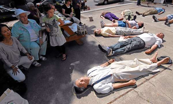 Lying on the pavement, Masanabu Ikemya (in foreground) of Bar Harbor and others participated in a symbolic "die-in" during Friday afternoon's Hiroshima Commemoration at Pierce Park next to Bangor Public Library. On the far left (kneeling) was Ikemya's wife Tomoko Ikeyima later read a childrens' picture card story with her husband regarding the Hiroshima bombing in 1945. (Bangor Daily News/John Clarke Russ) Lying on the pavement, Masanabu Ikemya (in foreground) of Bar Harbor and others participated in a symbolic "die-in" during Friday afternoon's Hiroshima Commemoration at Pierce Park next to Bangor Public Library. On the far left (kneeling) was Ikemya's wife Tomoko Ikeyima later read a childrens' picture card story with her husband regarding the Hiroshima bombing in 1945. (Bangor Daily News/John Clarke Russ)