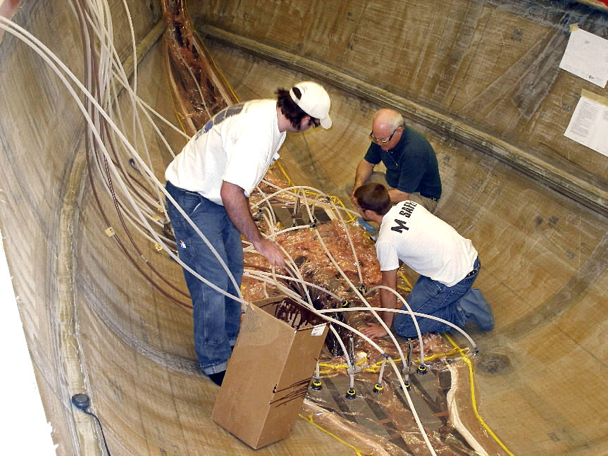 Peter Smith, the chief engineer at Morris Yachts, right, Sky Winn and Jake Belhumer, monitor the infusion lines Thursday on the hull of a 44-foot sailboat that the boatyard is building for the sail Leadership program at the U.S. Coast Guard Academy. The process joined the two halves of the hull together. This is the first of eight sailboats, each costing more than $800,000, the boatyard expects to build over the next two years. (Bangor Daily News/Rich Hewitt) Peter Smith, the chief engineer at Morris Yachts, right, Sky Winn and Jake Belhumer, monitor the infusion lines Thursday on the hull of a 44-foot sailboat that the boatyard is building for the sail Leadership program at the U.S. Coast Guard Academy. The process joined the two halves of the hull together. This is the first of eight sailboats, each costing more than $800,000, the boatyard expects to build over the next two years. (Bangor Daily News/Rich Hewitt)