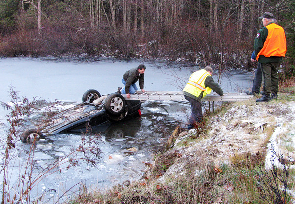 Morrill Fire Chief Pat Scribner crawls across a ladder Friday afternoon to attach a cable to the partially-submerged car that had flipped into a pond off Poland Woods Road. The driver, 20-year-old Jacob Mehuren of Brooks, was able to squeeze out a broken window and suffered only mild hypothermia. (Abigail Curtis/ BDN) Morrill Fire Chief Pat Scribner crawls across a ladder Friday afternoon to attach a cable to the partially-submerged car that had flipped into a pond off Poland Woods Road. The driver, 20-year-old Jacob Mehuren of Brooks, was able to squeeze out a broken window and suffered only mild hypothermia. (Abigail Curtis/ BDN)