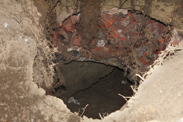 BANGOR - A sinkhole that opened up about noon Friday in Norumbega Parkway, a city park between State and Franklin streets that is bordered by the Kenduskeag Stream, was cited as the cause of a machinery mishap. Bangor Public Works Director Dana Wardwell said Friday night that a piece of heavy machinery - known as a man lift, bucket truck or cherry picker - was in the parkway as part of an inspection of historic Norumbega Hall, the large brick building that houses Eastern Maine Development Corp. and the University of Maine Museum of Art, when the sinkhole appeared and the machine sank into it. Wardwell said it was not yet clear what caused the hole, which he said is about 15 feet deep and about 4 feet in diameter at its top and larger at the bottom. He said the hole could have resulted from erosion from the Kenduskeag Stream or from the collapse of an old pipe. (Photo courtesy of Tony DelMonaco) BANGOR - A sinkhole that opened up about noon Friday in Norumbega Parkway, a city park between State and Franklin streets that is bordered by the Kenduskeag Stream, was cited as the cause of a machinery mishap. Bangor Public Works Director Dana Wardwell said Friday night that a piece of heavy machinery - known as a man lift, bucket truck or cherry picker - was in the parkway as part of an inspection of historic Norumbega Hall, the large brick building that houses Eastern Maine Development Corp. and the University of Maine Museum of Art, when the sinkhole appeared and the machine sank into it. Wardwell said it was not yet clear what caused the hole, which he said is about 15 feet deep and about 4 feet in diameter at its top and larger at the bottom. He said the hole could have resulted from erosion from the Kenduskeag Stream or from the collapse of an old pipe. (Photo courtesy of Tony DelMonaco)