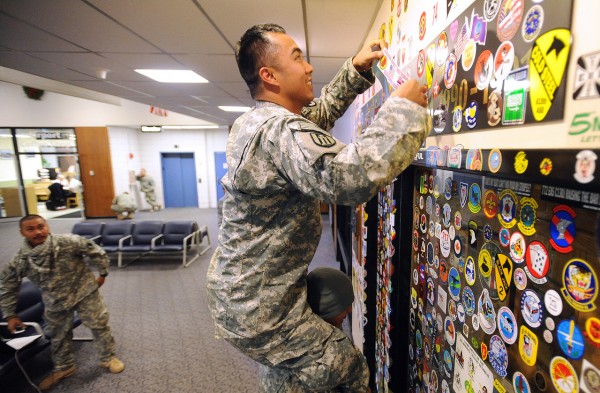 Sgt. Jake Garcia puts a sticker of his unit onto the wall as he sits oon the shoulders of Spc. Andre Varea at the Bangor International Airport New Year's Eve 2010. They are among the 117 membes of the Hawaii Army National Guard 230th Engineer Company that made a stop in Bangor on their way home from Afghanistan. They hope to arrive in Hickman, Hawaii sometime in the morning on January 1st 2011. (Bangor Daily News/Gabor Degre) Sgt. Jake Garcia puts a sticker of his unit onto the wall as he sits oon the shoulders of Spc. Andre Varea at the Bangor International Airport New Year's Eve 2010. They are among the 117 membes of the Hawaii Army National Guard 230th Engineer Company that made a stop in Bangor on their way home from Afghanistan. They hope to arrive in Hickman, Hawaii sometime in the morning on January 1st 2011. (Bangor Daily News/Gabor Degre)