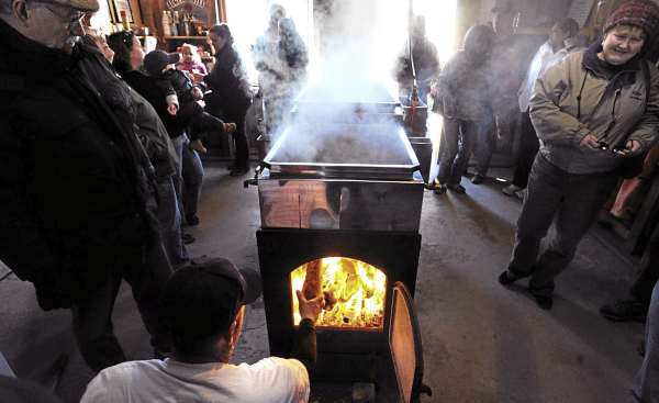 Visitors look on as Chris Getchell (bottom) loads wood into the firebox of the evapotator while making maple syrup at the Auger Hill Farm in Marshfiled Sunday. Owner Walter Getchel said that it is hectic to open the farm to the public on Maine Maple Sunday but it is also a lot of fun. This is more like a social event and a reason to hang out together said Chris Getchell who helps out his uncle during the maple syrup season. Visitors look on as Chris Getchell (bottom) loads wood into the firebox of the evapotator while making maple syrup at the Auger Hill Farm in Marshfiled Sunday. Owner Walter Getchel said that it is hectic to open the farm to the public on Maine Maple Sunday but it is also a lot of fun. This is more like a social event and a reason to hang out together said Chris Getchell who helps out his uncle during the maple syrup season.