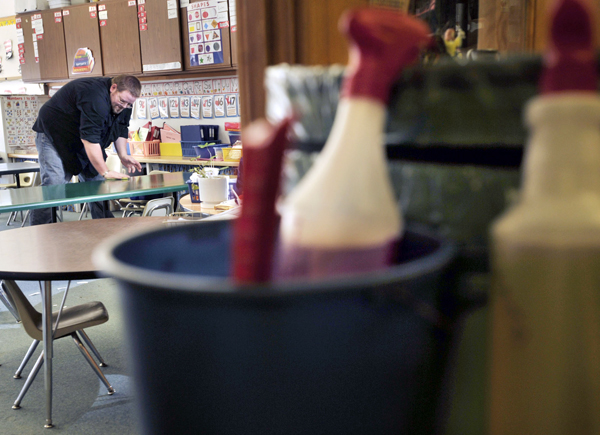 Custodian Carl Crossman wipes down classroom tables as he makes his rounds through the Capri street school in Brewer Tuesday. Custodian Carl Crossman wipes down classroom tables as he makes his rounds through the Capri street school in Brewer Tuesday.