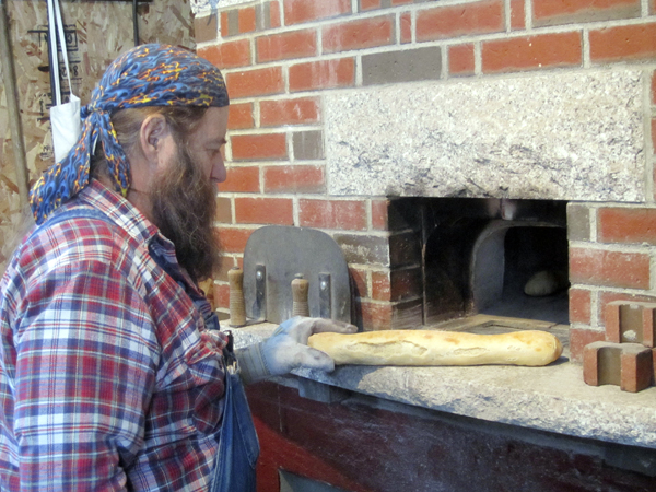 Dusty pulling a fresh baked baguette from his wood-fired bread oven. Dusty pulling a fresh baked baguette from his wood-fired bread oven.