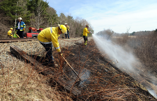 Firefighters from Carmel, Etna and Levant work to put out hot spots along railroad tracks near the town's recreation fields on Tuesday. Firefighters from Carmel, Etna and Levant work to put out hot spots along railroad tracks near the town's recreation fields on Tuesday.