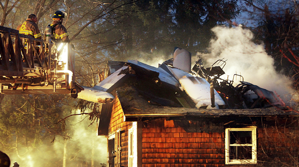 Firemen work at the scene where a small plane crashed into a house near the Biddeford, Maine, Municipal Airport Sunday evening. The Federal Aviation Administration said at least one person in the plane died in the crash. Firemen work at the scene where a small plane crashed into a house near the Biddeford, Maine, Municipal Airport Sunday evening. The Federal Aviation Administration said at least one person in the plane died in the crash.