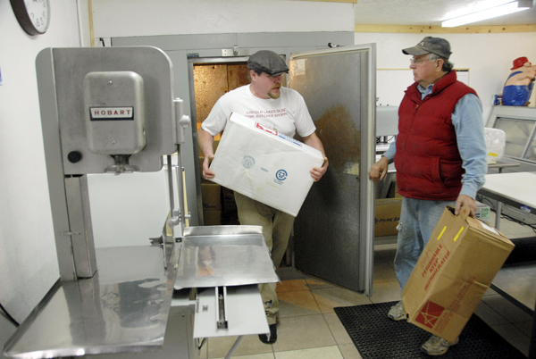 Errol Libby Jr. carries a box of meat from his walk-in refrigerator as his father, Errol Sr., talks as they prepare to open the family's Lincoln Lakes Olde Tyme Butcher Shoppe in Lincoln on Thursday. Errol Libby Jr. carries a box of meat from his walk-in refrigerator as his father, Errol Sr., talks as they prepare to open the family's Lincoln Lakes Olde Tyme Butcher Shoppe in Lincoln on Thursday.