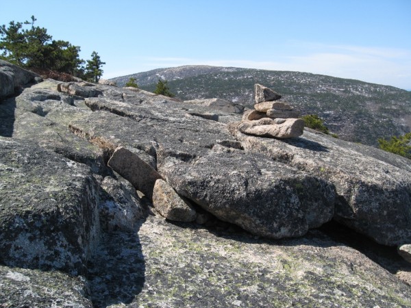 Cairns like this one mark the trail near the summit of Champlain Mountain. Cadillac Mountain rises in the distance in the view from the Bear Brook Trail. Cairns like this one mark the trail near the summit of Champlain Mountain. Cadillac Mountain rises in the distance in the view from the Bear Brook Trail.