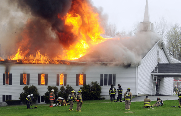 Firefighters from numerous departements pull back as the roof collapses on the Calvary Apostolic Church in Winterport on Thursday. Firefighters from numerous departements pull back as the roof collapses on the Calvary Apostolic Church in Winterport on Thursday.