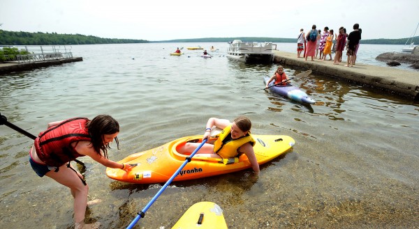 Aebie Blauvelt, 11, of Rumford gives Margo Roberts, 12, of Bangor a hand with landing her kayak after a morning outing on Branch Lake at Camp Rainbow in Ellsworth on Tuesday. They were among the 45 people who attend Camp Rainbow that provides a free week-long summer camp for children diagnosed with cancer and their families. This is the 24th annual camp that is offered by the American Cancer Society. Aebie Blauvelt, 11, of Rumford gives Margo Roberts, 12, of Bangor a hand with landing her kayak after a morning outing on Branch Lake at Camp Rainbow in Ellsworth on Tuesday. They were among the 45 people who attend Camp Rainbow that provides a free week-long summer camp for children diagnosed with cancer and their families. This is the 24th annual camp that is offered by the American Cancer Society.