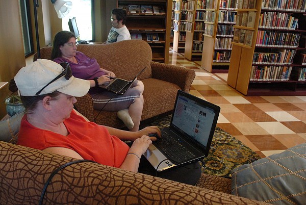 Rebecca Wilson (left) of Old Town, Shannon Buck (center) of Greenbush, and Charles Rogan (right, in background) of Orono, access the internet at the Old Town Public Library in Old Town on Wednesday, June 22, 2011. Wilson says that she comes to the library almost every day to use the free wireless internet, while her 12-year-old son often joins her and checks out books. According to library director Cynthia Jennings, in recent years the library has undergone a transition, attracting new patrons through innovative programming and by "creating spaces so people come and stay." Jennings said that in addition to increased educational and entertainment programs, comfortable inside spaces and relaxing outside gardens have helped make the Old Town library a desirable meeting place for homeschooling groups, business training seminars, quilting groups, independent book groups and community forums. Jennings stated, "One of our goals is to become a destination instead of a transaction library." Rebecca Wilson (left) of Old Town, Shannon Buck (center) of Greenbush, and Charles Rogan (right, in background) of Orono, access the internet at the Old Town Public Library in Old Town on Wednesday, June 22, 2011. Wilson says that she comes to the library almost every day to use the free wireless internet, while her 12-year-old son often joins her and checks out books. According to library director Cynthia Jennings, in recent years the library has undergone a transition, attracting new patrons through innovative programming and by "creating spaces so people come and stay." Jennings said that in addition to increased educational and entertainment programs, comfortable inside spaces and relaxing outside gardens have helped make the Old Town library a desirable meeting place for homeschooling groups, business training seminars, quilting groups, independent book groups and community forums. Jennings stated, "One of our goals is to become a destination instead of a transaction library."