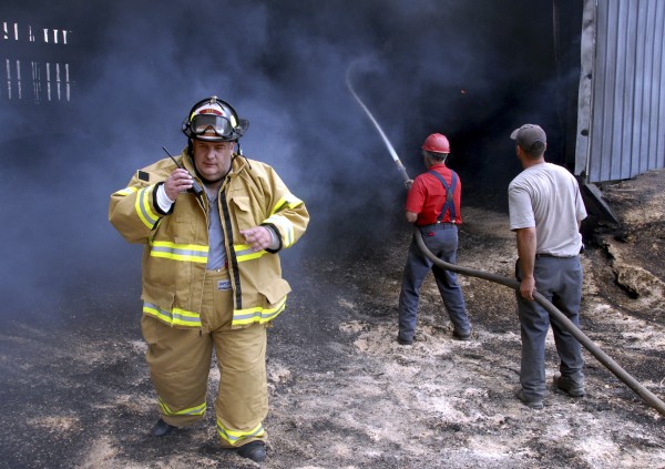 Mattawamkeag firefighter Michael Coombs listens to his two-way radio as electrician Michael Rioux and an unidentified man douse hot spots in an attached shed at the Chester Forest Products sawmill in Chester on Friday, July 15, 2011. Mattawamkeag firefighter Michael Coombs listens to his two-way radio as electrician Michael Rioux and an unidentified man douse hot spots in an attached shed at the Chester Forest Products sawmill in Chester on Friday, July 15, 2011.