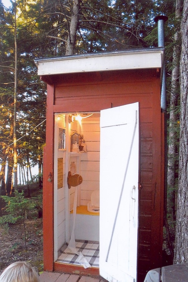 I am an outhouse located at Beech Hill Pond. I have had three owners over the years. I was born in 1950 on the West Shore Road and have had many good years. There are many attributes that make me a unique outhouse. I am able to host two users at the same time, I have electricity, I am painted and decorated, and now I have a new tiled floor. But I have not always been so impressive.
During my life with my second owner, I began to deteriorate. I need a new skirt, new paint, roof work, and most of all a new floor. On the 4th of July celebrations of 2000, I was hosting two users. When they were doing their thing, my floor gave way and the larger of the two woman dropped six feet to the bottom of the outhouse. It required a ladder to get her out.
Needless to say, the lady never returned to visit me and shortly after this traumatic event the camp was sold to the current owners. They have turned me around and given me a second life. I now have new paint inside and out, a new skirt, better lighting and most importantly a new floor to host my guests.
With my second chance of life I feel I am one of the best outhouses out there. I have many friends on Beech Hill Pond, and I am by far the most attractive outhouse of them all.