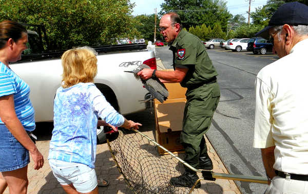 Residents of Barker Mill Arms in Auburn help Game Warden Rick Stone rescue an injured great blue heron from the Little Androscoggin River on Wednesday afternoon. The residents called Stone after noticing the creature's wing was apparently injured. Residents of Barker Mill Arms in Auburn help Game Warden Rick Stone rescue an injured great blue heron from the Little Androscoggin River on Wednesday afternoon. The residents called Stone after noticing the creature's wing was apparently injured.
