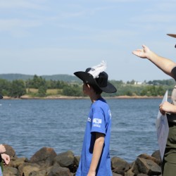 Standing on Red Beach, Lauren McGrath (right), a park ranger and language interpreter with the National Park Service, gestures towards St. Croix Island International Historic Site while giving visitors a history lesson about the island on Aug. 1, 2011.