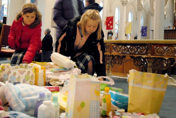 Meghan Harriman and Jayda Bailey from All Saints Catholic School lay gifts on the altar beneath a statue of Mary at St. John's Catholic Church Thursday morning in Bangor. Meghan Harriman and Jayda Bailey from All Saints Catholic School lay gifts on the altar beneath a statue of Mary at St. John's Catholic Church Thursday morning in Bangor.
