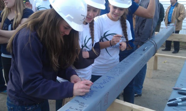 Old Town High School student Lauren Tibbits (left), 15, signs her name on one of the last two steel beams lifted onto the school's science and art expansion wing on Tuesday. Fellow students Karah Hussey (center), 14, and Rachel Martin (right), 15, watch Tibbits after signing their own names. Old Town High School student Lauren Tibbits (left), 15, signs her name on one of the last two steel beams lifted onto the school's science and art expansion wing on Tuesday. Fellow students Karah Hussey (center), 14, and Rachel Martin (right), 15, watch Tibbits after signing their own names.