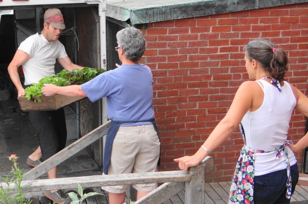 Freddy Lafage passes produce to Karen Campbell as part of the 11 a.m. produce sale featured at Chase's Daily restaurant in Belfast. Freddy Lafage passes produce to Karen Campbell as part of the 11 a.m. produce sale featured at Chase's Daily restaurant in Belfast.