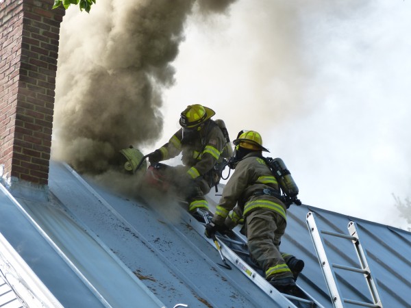 Firefighters use a power saw to cut through the metal roof of a two-story farmhouse at 246 Coombs Road in Brunswick to vent the smoke. Firefighters use a power saw to cut through the metal roof of a two-story farmhouse at 246 Coombs Road in Brunswick to vent the smoke.