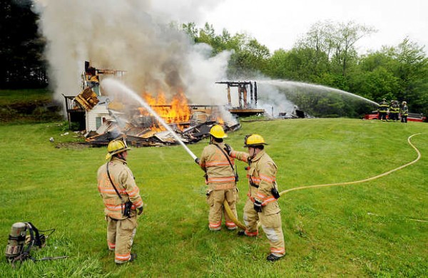 Firefighters from Poland, left, and Minot, right, battle the fire at 185 Verrill Road in Minot on Friday. Firefighters from Poland, left, and Minot, right, battle the fire at 185 Verrill Road in Minot on Friday.