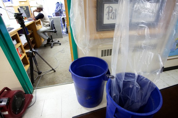Willy Katihabwa works in the office at Portland Adult Education on Wednesday amid plastic sheeting a barrels collecting rainwater that percolates through the roof. Willy Katihabwa works in the office at Portland Adult Education on Wednesday amid plastic sheeting a barrels collecting rainwater that percolates through the roof.