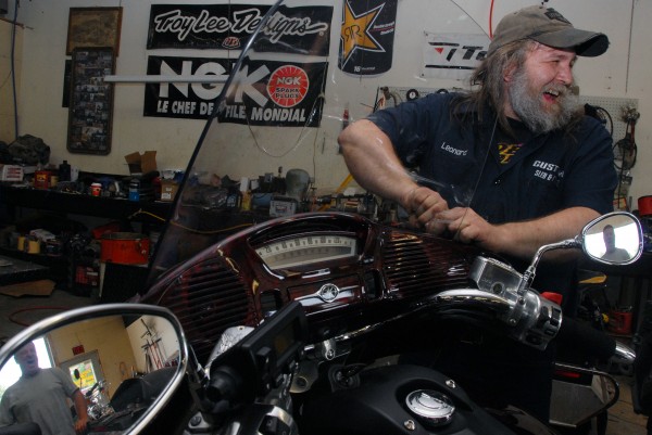 Leonard Jacobs, a mechanic at Custom Sled & Cycle of Medway, laughs with customer Ricky Morse of Patten (reflected in mirrors) as he works on Morse's motorcycle on Thursday, June 6, 2013. Leonard Jacobs, a mechanic at Custom Sled & Cycle of Medway, laughs with customer Ricky Morse of Patten (reflected in mirrors) as he works on Morse's motorcycle on Thursday, June 6, 2013.