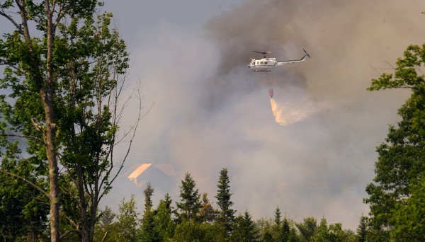 A helicopter drops water on an intense forest fire in Newburgh Tuesday afternoon. A helicopter drops water on an intense forest fire in Newburgh Tuesday afternoon.