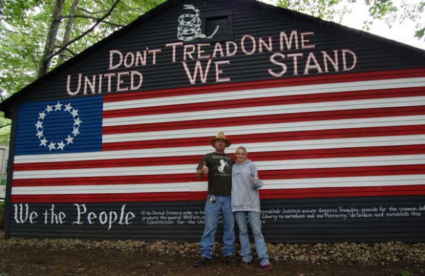 Benjamin Jacques and his girlfriend, Samantha Bell, stand front of a painting of an early U.S. flag on the back of garage that was spray-painted with black paint on June 20. He is offering a $500 reward for the "capture and conviction" of the person responsible. Benjamin Jacques and his girlfriend, Samantha Bell, stand front of a painting of an early U.S. flag on the back of garage that was spray-painted with black paint on June 20. He is offering a $500 reward for the "capture and conviction" of the person responsible.