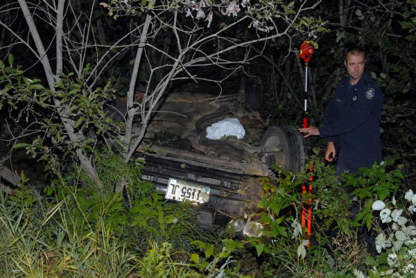 State police Trooper Larry Anderson takes measurements from the sedan that veered from Aroostook Road and crashed in Molunkus on Monday, Aug. 26, 2013. State police Trooper Larry Anderson takes measurements from the sedan that veered from Aroostook Road and crashed in Molunkus on Monday, Aug. 26, 2013.