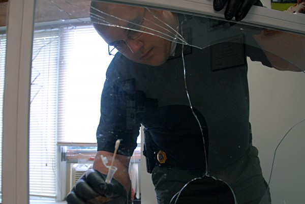 Lincoln police Detective Mark Fucile swabs DNA samples from a window broken during burglaries at four West Broadway businesses on Friday, Aug. 23, 2013. Lincoln police Detective Mark Fucile swabs DNA samples from a window broken during burglaries at four West Broadway businesses on Friday, Aug. 23, 2013.