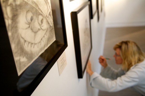 Sandy Comstock hangs art at the Portland Public Library on Thursday. From Sept. 6 to Oct. 25, the Maine College of Art and the library is presenting a special exhibition called "Maurice Sendak: 50 Years, 50 Works, 50 Reasons." The exhibition includes 50 original works from Where the Wild Things Are in a variety of mediums including sketches, illustrations, and works on paper, and showcases highlights from Sendakâs career and the diverse art forms. Sandy Comstock hangs art at the Portland Public Library on Thursday. From Sept. 6 to Oct. 25, the Maine College of Art and the library is presenting a special exhibition called "Maurice Sendak: 50 Years, 50 Works, 50 Reasons." The exhibition includes 50 original works from Where the Wild Things Are in a variety of mediums including sketches, illustrations, and works on paper, and showcases highlights from Sendakâs career and the diverse art forms.