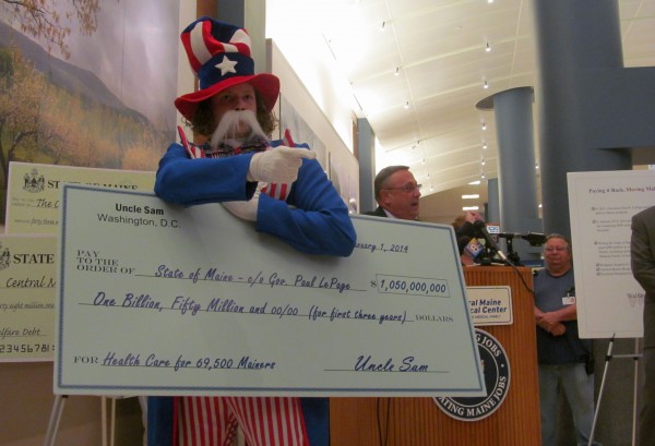 A protester from Maine People's Alliance holds a huge check representing the $1.05 billion federal funding available to Maine for Medicaid expansion. This spring, Gov. LePage vetoed a bipartisan bill to accept the money and expand publicly funded health insurance for roughly 70,000 Mainers. A protester from Maine People's Alliance holds a huge check representing the $1.05 billion federal funding available to Maine for Medicaid expansion. This spring, Gov. LePage vetoed a bipartisan bill to accept the money and expand publicly funded health insurance for roughly 70,000 Mainers.
