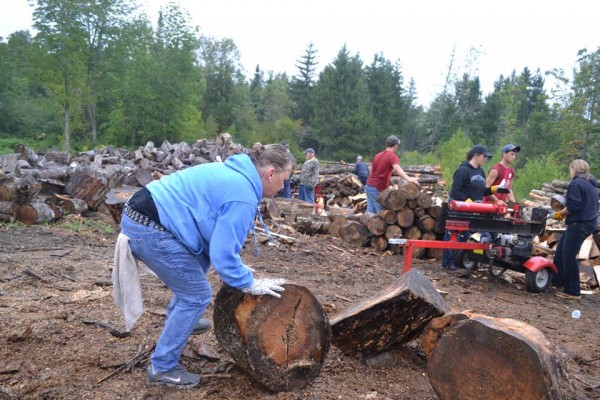 Kim Heath of Bangor, who works for T & D Equipment Repair in Glenburn, rolls a piece of wood towards the wood splitter on Sunday in Holden. Heath and was one of 50 local businesspeople who came together to assist Holden resident Rick Whitmore, who has been unable to work because he's battling nasal cancer. Whitmore is the project manager for Gary Pomeroy Logging Inc. in Hermon and has a side job delivering firewood. Kim Heath of Bangor, who works for T & D Equipment Repair in Glenburn, rolls a piece of wood towards the wood splitter on Sunday in Holden. Heath and was one of 50 local businesspeople who came together to assist Holden resident Rick Whitmore, who has been unable to work because he's battling nasal cancer. Whitmore is the project manager for Gary Pomeroy Logging Inc. in Hermon and has a side job delivering firewood.