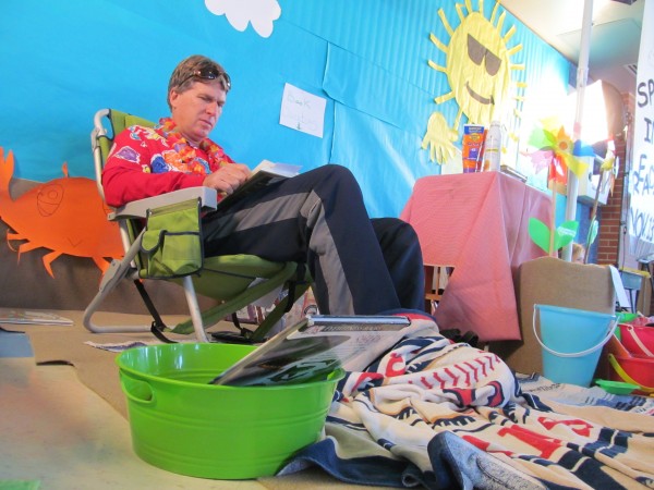 Lyman Moore Middle School Principal Stephen Rogers reads the new John Grisham novel "Sycamore Row" Wednesday surrounded by beach decorations in the school lobby. Rogers vowed to read from the opening bell to the closing bell as part of a Pizza Hut-sponsored challenge. By participating, Rogers is in the running to win 101 copies of "Diary of a Wimpy Kid: Hard Luck" for his school. Lyman Moore Middle School Principal Stephen Rogers reads the new John Grisham novel "Sycamore Row" Wednesday surrounded by beach decorations in the school lobby. Rogers vowed to read from the opening bell to the closing bell as part of a Pizza Hut-sponsored challenge. By participating, Rogers is in the running to win 101 copies of "Diary of a Wimpy Kid: Hard Luck" for his school.