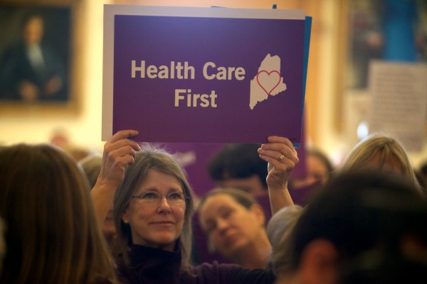 A woman holds a sign at a rally and lobby day organized by the Maine Peoples Alliance at the State House in Augusta on Jan. 8 around the issue of Medicaid expansion. A woman holds a sign at a rally and lobby day organized by the Maine Peoples Alliance at the State House in Augusta on Jan. 8 around the issue of Medicaid expansion.
