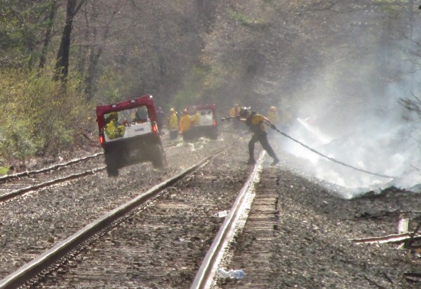 A firefighter drags hose from a tanker truck parked nearby, through a wooded area and onto an otherwise remote section of railroad tracks in Old Orchard Beach on Thursday night. A firefighter drags hose from a tanker truck parked nearby, through a wooded area and onto an otherwise remote section of railroad tracks in Old Orchard Beach on Thursday night.