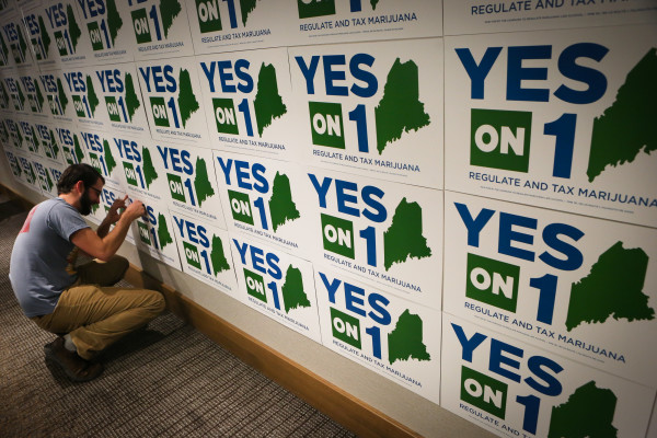 Nick Murray pins a sign to a wall at the Yes on 1 election night headquarters in Portland on Tuesday night.