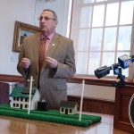 Gov. Paul LePage uses a model of a home selling solar power to the electric grid during a press conference at the State House to decry a recent decision by the Public Utilities Commission that he says will force Maine ratepayers to subsidize the solar industry.