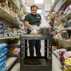 Ben Dionne stacks seeds on the shelves at Paris Farmers Union in Lewiston, where he works part-time. He was hired due to the help of vocational rehabilitation.