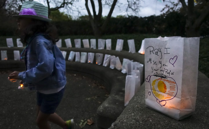 A young volunteer helps set up lights in paper bags decorated with messages for the deceased during an Out of the Darkness Walk event organized by the Cincinnati Chapter of the American Foundation for Suicide Prevention in Sawyer Point park in Cincinnati, Oct. 15, 2017.